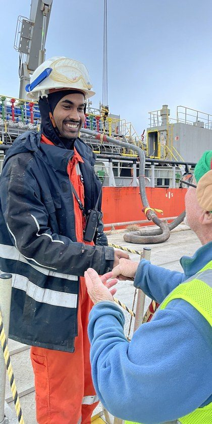 A crew member greeting an older volunteer on the ship deck