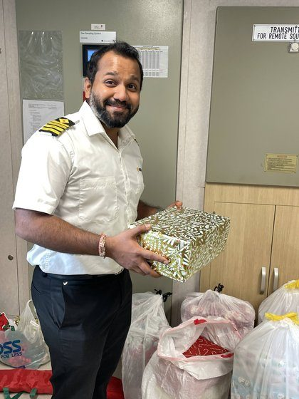 A crew member holding a wrapped Christmas gift in the office