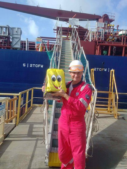 A crew member holding a smiley-face welcome bag