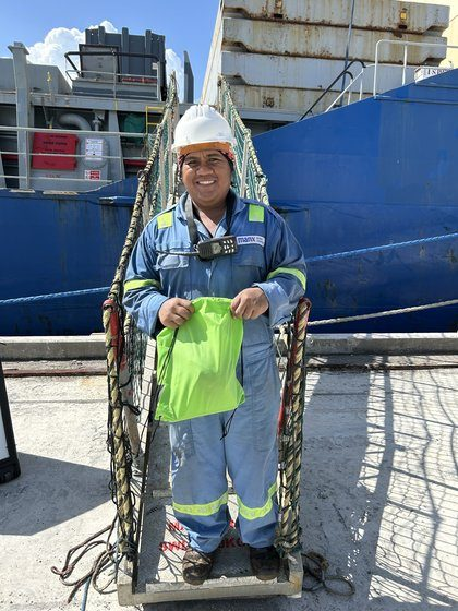 A crew member holding a welcome bag on the gangway