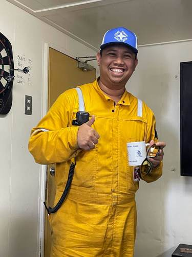 Crew member smiling with a Point Comfort Seafarers Center mug inside the center