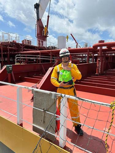 Crew member holding a green welcome bag on a ship deck