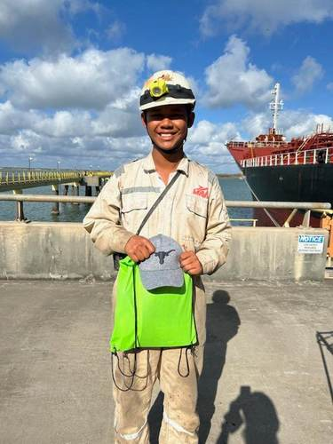 Young crew member holding a green welcome bag on the dock
