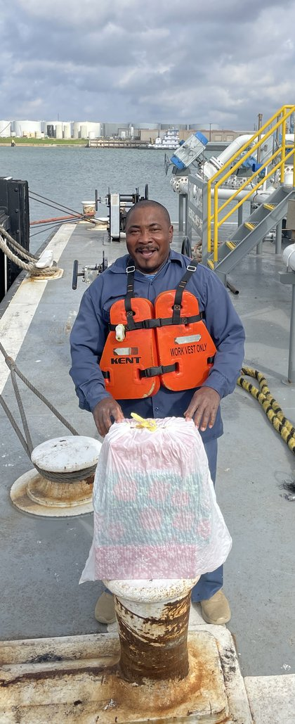 A crew member holding a wrapped gift on the dock