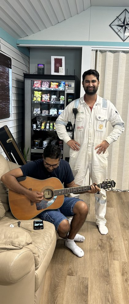 A crew member and a guest playing guitar inside the Seafarers Center lounge
