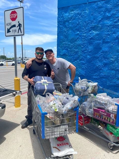 Two crew members with shopping carts of donated supplies outside a store