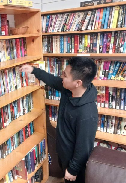 A volunteer browsing the book and puzzle shelves